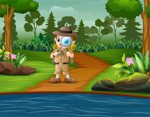 Boy explorer with magnifying glass in the forest