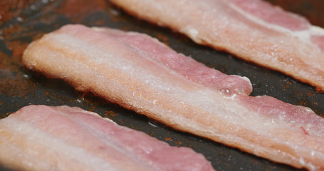 Fry bacon in pan in kitchen for breakfast