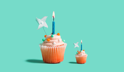 Big and small celebratory cupcakes with decorative lit candles