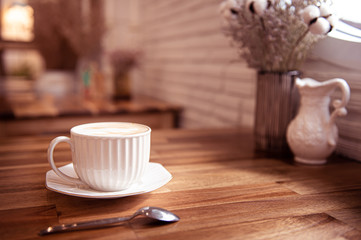 Coffee cup on wood table near window in blur background.