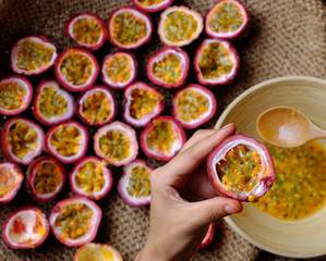 woman hand take soft pulp and seeds inside passion fruit cut in half