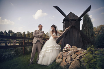 the concept of a romantic walk. A loving couple holding hands. Bride and groom at the little mill. Concept of household, production of flour, bread, interior, wedding fashion