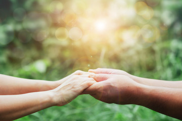 Close up of Two people holding hand together over blurred green nature garden background, Business man and woman shaking hands, helping hand and teamwork  concept with copy space