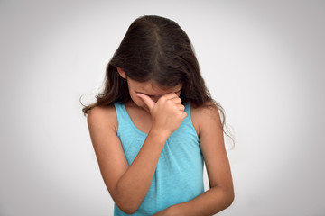 Fototapeta premium Sad, unhappy and crying young girl with hand on her face. Childhood and expressions concept. 