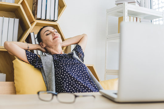 Businesswoman Laid Back On The Chair With Hands Behind Her Head In The Office. 