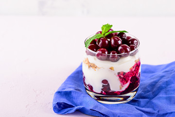 horizontally glass with berry Breakfast, dessert of ripe cherries, granola and ricotta cheese with copy space