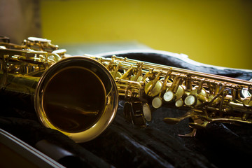 close up of alto saxophone in open case on table against widow light, copy space