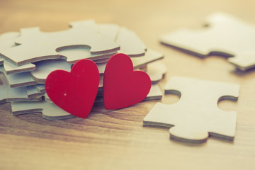 Close up of red heart over pile of jigsaws on wooden table, Conceptual image show most important part of human life is love