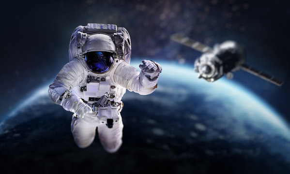 Astronaut in the outer space over the planet Earth. Space craft behind. Spaceship. Spaceman. Elements of this image furnished by NASA