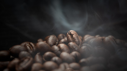 Aroma roasted coffee beans with smoke rising over dark background - obrazy, fototapety, plakaty