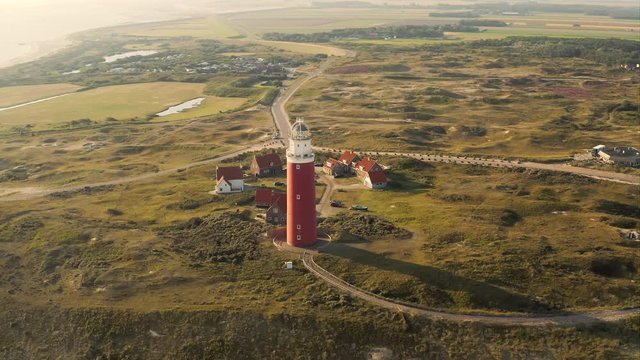 Aerial orbiting shot of the beautiful lighthouse at the Texel island (part of Wadden islands) in The Netherlands, shot in the morning after sunrise