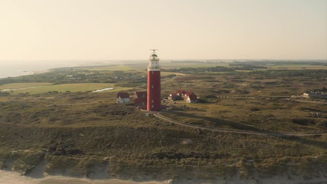 Aerial orbiting shot (low angle) of the beautiful lighthouse at the Texel island (part of Wadden islands) in The Netherlands, shot in the morning after sunrise