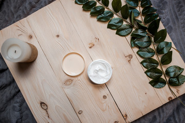 White body cream on the white wooden background. Soft body cream with green leaves and cotton around.