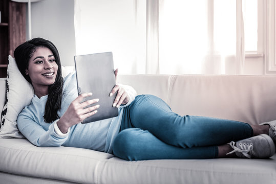 Appealing dark-haired female making photo with her tablet