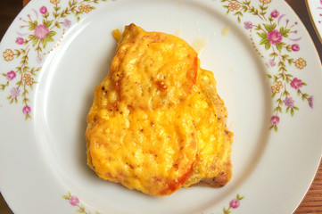 Baked meat with tomatoes and cheese on a white plate, view from the top close up