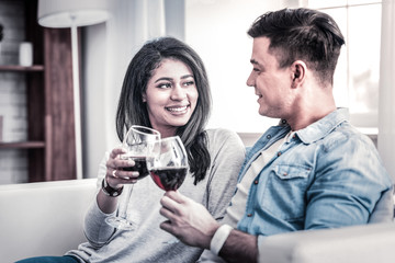 Openly smiling African American woman clinking wine glasses