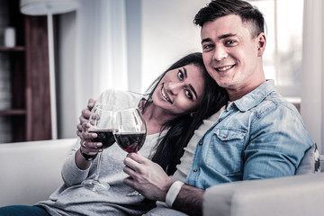 International couple drinking red wine while hugging