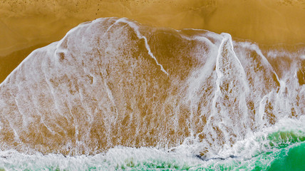 Top view of the beautiful sandy beach with turquoise sea water. Aerial drone shot at the big ocean waves on the West coast. a deserted beach for travel and recreation