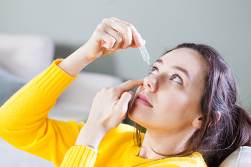 Closeup view of young woman applying eye drop, artificial tears..