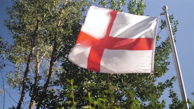 English National Flag St George's Cross Flying in the wind against Green foliage background