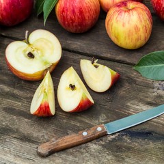 Red apple sliced and knife on old wooden table