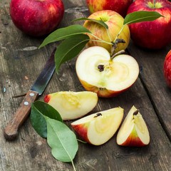 Red apple sliced and knife on old wooden table