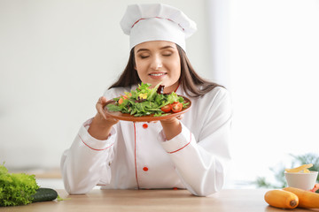 Beautiful female chef with salad in kitchen