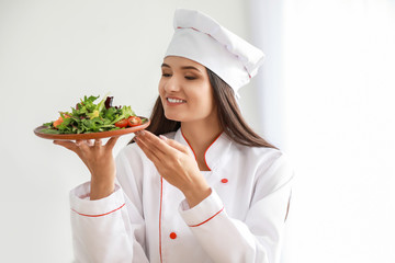 Beautiful female chef with salad in kitchen