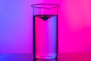 Chemical glassware close up on neon pink-purple background