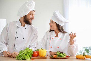 Professional chefs preparing vegetable salad in kitchen