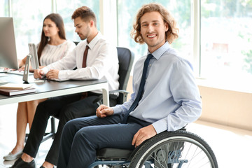 Handicapped young man with colleagues working in office