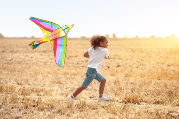 Little African-American girl flying kite outdoors