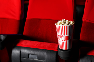 Cup of popcorn on chair in empty cinema