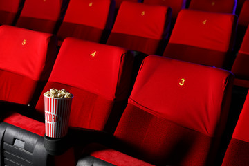 Cup of popcorn on chair in empty cinema