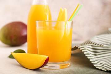 Glass and bottle of tasty mango juice on table