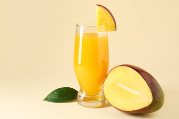 Glass of tasty mango juice on color background