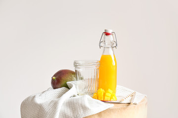 Bottle of tasty mango juice and glass on table