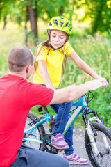 Obraz premium Father communicates with his daughter, teaching her how to ride a bicycle