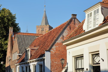 Historic houses located inside the fortified town of Naarden, Netherlands, with the clock tower of the Grote Kerk church in the background