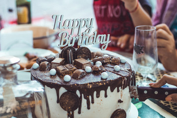 Chocolate Cake with Happy Birthday sign being served a large portion sliced from the cake. Celebration and holidays concept.