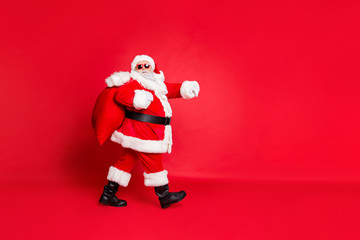Full length body size view of his he funky fat overweight plump gray-haired bearded man piggy backing gifts fairy going to children house home isolated over bright vivid shine red background