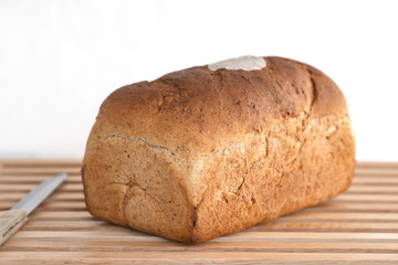 Homemade loaf of bread with knife against white background