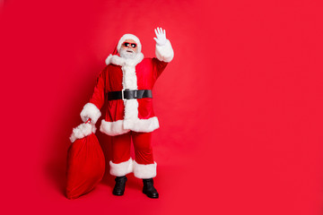 Full length body size view of his he cheerful funky fat overweight plump gray-haired bearded man carrying purchases waving greetings congrats tradition isolated over bright vivid shine red background