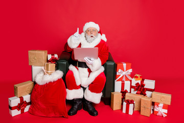 Full body photo of impressed santa claus with eyewear eyeglasses spectacles use device have genius thoughts wearing headwear hat belt isolated over red background