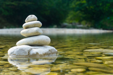Harmony, balance and simplicity concept. A stone pyramid on the background of river water. Simple poise pebbles, rock zen sculpture