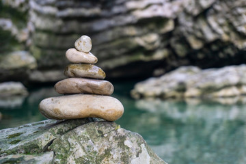 Harmony, balance and simplicity concept. A stone pyramid on the background of river water. Simple poise pebbles, rock zen sculpture