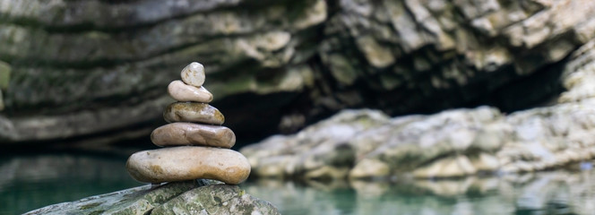 Fototapeta na wymiar Harmony, balance and simplicity concept. A stone pyramid on the background of river water. Simple poise pebbles, rock zen sculpture