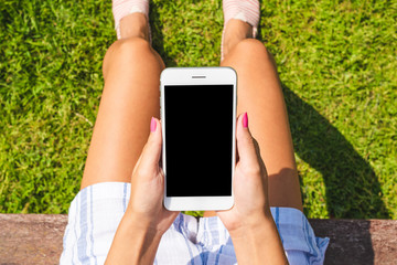 Young woman in summer outfit using smart phone with empty screen. Close up