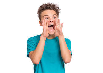 Attention! Portrait of teen boy is holding hand near his open mouth and screaming, isolated on white background. Cute caucasian young teenager shouting with hands cupped to his mouth.