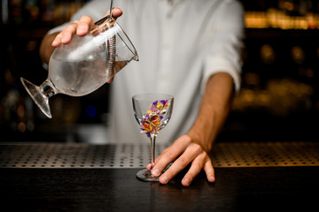 Bartender pouring alcohol from glass with strainer